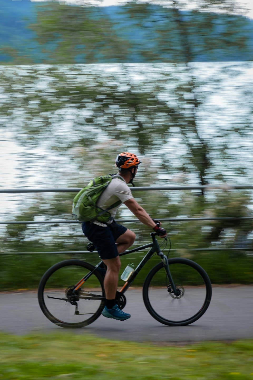 Kolarz jedzie rowerem górskim po utwardzonej ścieżce nadbrzeżnej.